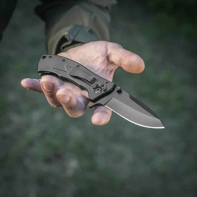 Navaja plegable tipo 7 M-Tac en mano, hoja plateada y empuñadura negra